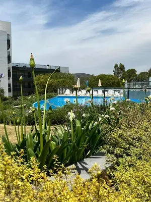 a garden with flowers and a swimming pool at Veneto Village Resort & Spa in Villa Carlos Paz