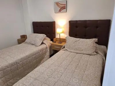 a bedroom with two beds and a table with a lamp at Depto Carlos I in Villa Carlos Paz