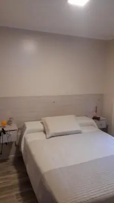 a bedroom with a large white bed with two tables at Depto Elba centro opcion cochera in Cordoba