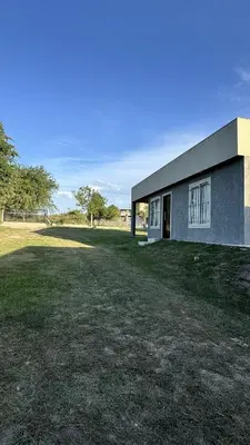 a building with a large yard in front of it at Cabañas cata 1 in Villa Santa Cruz del Lago