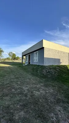 a building on a grass field next to a building at Cabañas cata 1 in Villa Santa Cruz del Lago
