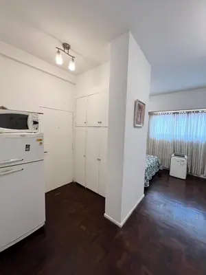a kitchen with white cabinets and a bed in a room at Bello Departamento PB en mejor zona de nva cba atencion personalizada in Cordoba