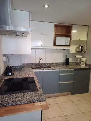 a kitchen with white cabinets and granite counter tops at Moderno departamento/Loft Córdoba - Coral State in Cordoba