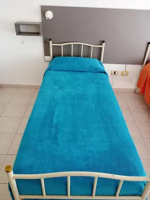 a bed with a blue blanket on it in a room at Kempes, Ferial Chateau in Cordoba