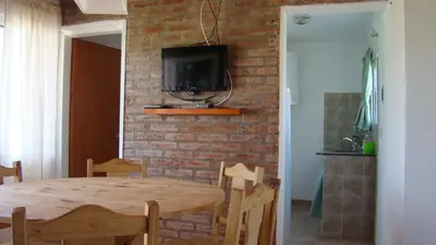 a dining room with a table and a tv on a brick wall at Remanso Los Molinos in Potrero de Garay