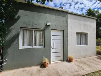 a green house with a white door and two windows at La Vivi in Villa Larca