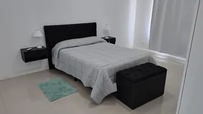 a bedroom with a black bed and a blue rug at Bienamada in Merlo