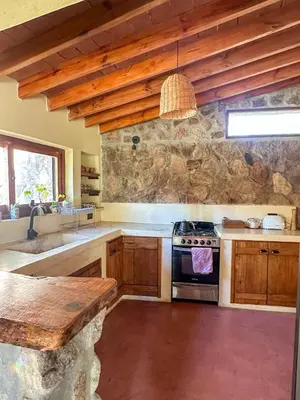 a kitchen with wooden cabinets and a stove top oven at Casa de piedra con jardin y pileta - privada in Los Hornillos