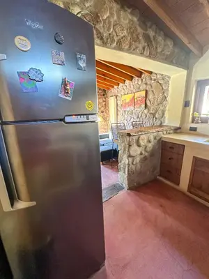 a stainless steel refrigerator in a kitchen with a stone wall at Casa de piedra con jardin y pileta - privada in Los Hornillos