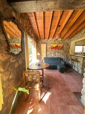 a living room with a table and a stone wall at Casa de piedra con jardin y pileta - privada in Los Hornillos