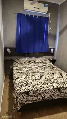 a bedroom with a leopard print bed with a blue curtain at Lo de Andrés y Marina in Arroyo de Los Patos