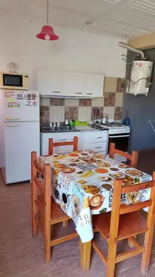a kitchen with a table with chairs and a refrigerator at Lo de Andrés y Marina in Arroyo de Los Patos