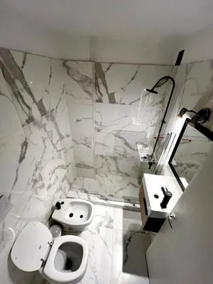 a white bathroom with a toilet and a sink at DEPARTAMENTO CENTRAL in Cordoba
