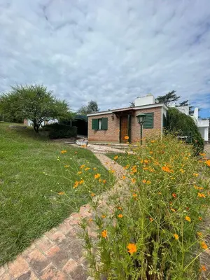 a house with a field of flowers in front of it at Petit House in Villa Carlos Paz