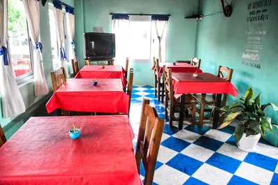 a restaurant with red tables and chairs in a room at El Quincho in Santa Rosa de Calamuchita