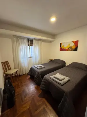 a hotel room with two beds and a chair at HERMOSO DEPARTAMENTO a 3 cuadras del PATIO OLMOS Dos dormitorios in Cordoba