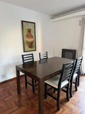 a dining room table with chairs and a vase on the wall at HERMOSO DEPARTAMENTO a 3 cuadras del PATIO OLMOS Dos dormitorios in Cordoba