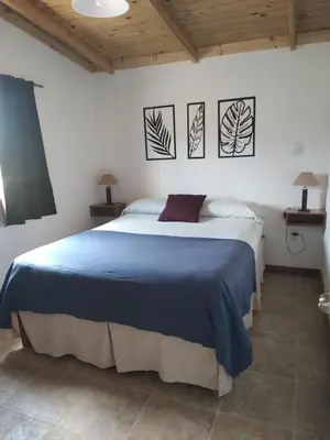 a bedroom with a blue bed with three pictures on the wall at Colinas del Mirador in Villa Carlos Paz