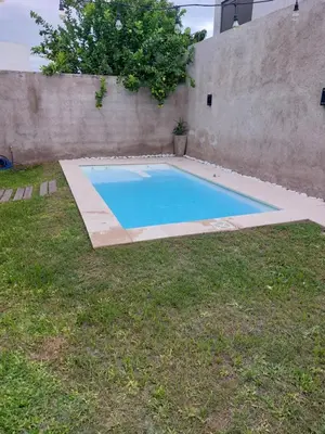 a swimming pool in a yard next to a wall at Casa de Descanso Valle Escondido in Cordoba