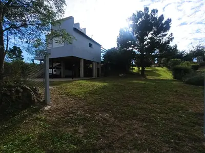 a house in a field with the sun in the background at Terrazas de Yacanto in Villa Yacanto