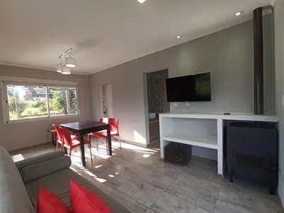 a living room with a television and a table with chairs at Terrazas de Yacanto in Villa Yacanto