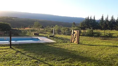 a pool in the middle of a field with a fence at Terrazas de Yacanto in Villa Yacanto