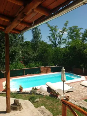 a swimming pool with a table and an umbrella at Cabañas Cangas de Onis MAYU SUMAJ in Villa Icho Cruz