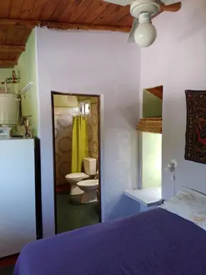 a bedroom with a bed and a bathroom with two toilets at Cabañas Cangas de Onis MAYU SUMAJ in Villa Icho Cruz