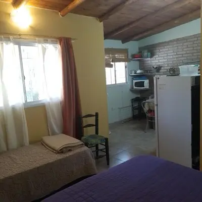 a room with a bed and a kitchen with a refrigerator at Cabañas Cangas de Onis MAYU SUMAJ in Villa Icho Cruz
