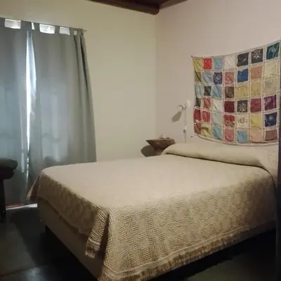 a bedroom with a bed with a quilt on it at Cabañas Cangas de Onis MAYU SUMAJ in Villa Icho Cruz