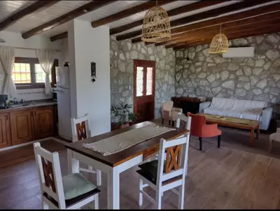 a kitchen and living room with a table and chairs at Cabaña de piedra Los Crespines in San Antonio de Arredondo