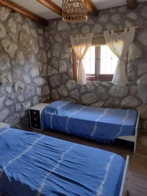 two beds in a room with a stone wall at Cabaña de piedra Los Crespines in San Antonio de Arredondo