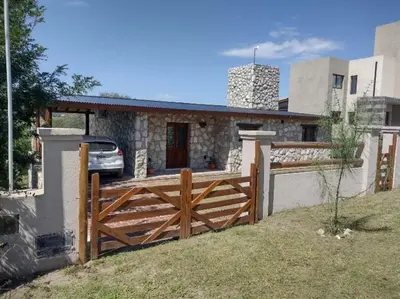 a house with a wooden fence in front of it at Cabaña de piedra Los Crespines in San Antonio de Arredondo
