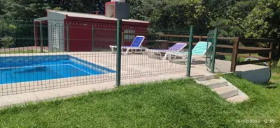 a swimming pool with two chairs next to a fence at Jasy Cabañas in Potrero de Garay