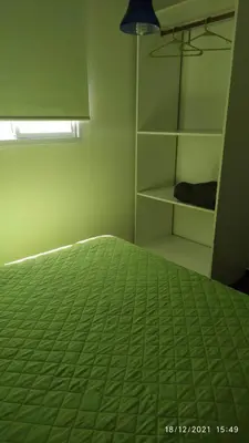 a bedroom with a bed with a green comforter at Jasy Cabañas in Potrero de Garay