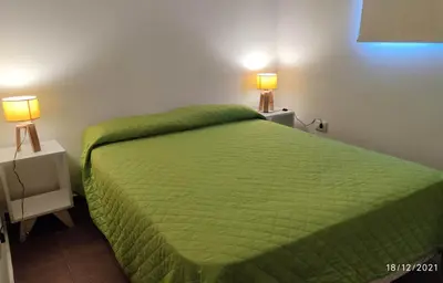 a bedroom with a green bed and two lamps on tables at Jasy Cabañas in Potrero de Garay