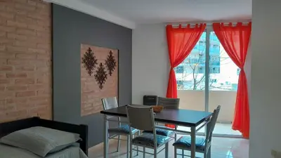 a dining room with a table and red curtains at Departamento Céntrico in Villa Carlos Paz