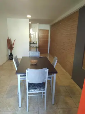 a dining room with a table and white chairs at Departamento Céntrico in Villa Carlos Paz