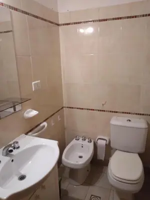 a bathroom with a white toilet and a sink at Departamento Céntrico in Villa Carlos Paz