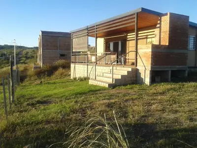 a house on top of a grassy hill at Estancia de Campo in Estancia Vieja