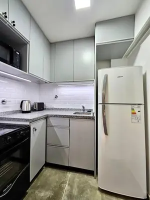 a white kitchen with a refrigerator and a stove at Departamento cálido y tranquilo SS2 in Cordoba