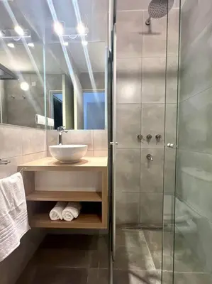 a bathroom with a glass shower and a sink at Departamento cálido y tranquilo SS2 in Cordoba