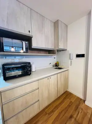 a kitchen with wooden cabinets and a microwave and a refrigerator at Departamento en hermosa zona de Nueva Córdoba. SS3 in Cordoba