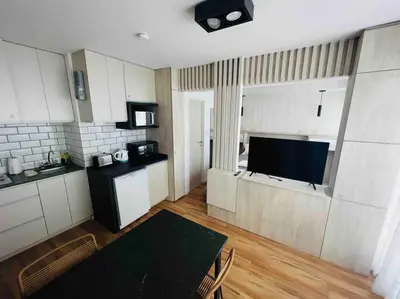 a kitchen with white cabinets and a table and a television at Estudio - apartamento renovado y confortable SS4 in Cordoba