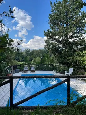 a swimming pool with two chairs and a fence at Cabañas el Bierzo in Villa Cura Brochero