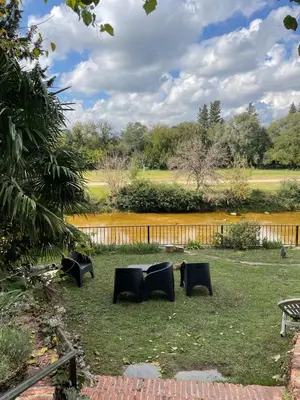 a group of chairs in the grass near a pond at Cabañas el Bierzo in Villa Cura Brochero