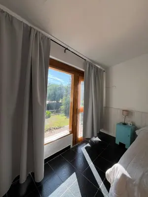 a bedroom with a bed and a large window at Cabañas el Bierzo in Villa Cura Brochero