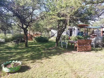 a yard with a table and a bench and trees at Posada Tinktinkie in Santa Rosa de Calamuchita