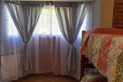 a bedroom with a window with curtains and a bed at Posada Tinktinkie in Santa Rosa de Calamuchita