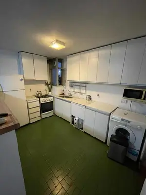 a kitchen with white cabinets and a green floor at Depto Nva Cba mts Parque Sarmiento in Cordoba